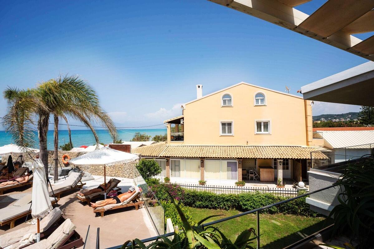 A two-story building with a balcony overlooking a beach.