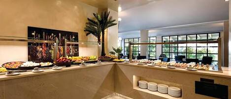 A buffet area with various food items, a large painting, and a palm tree.