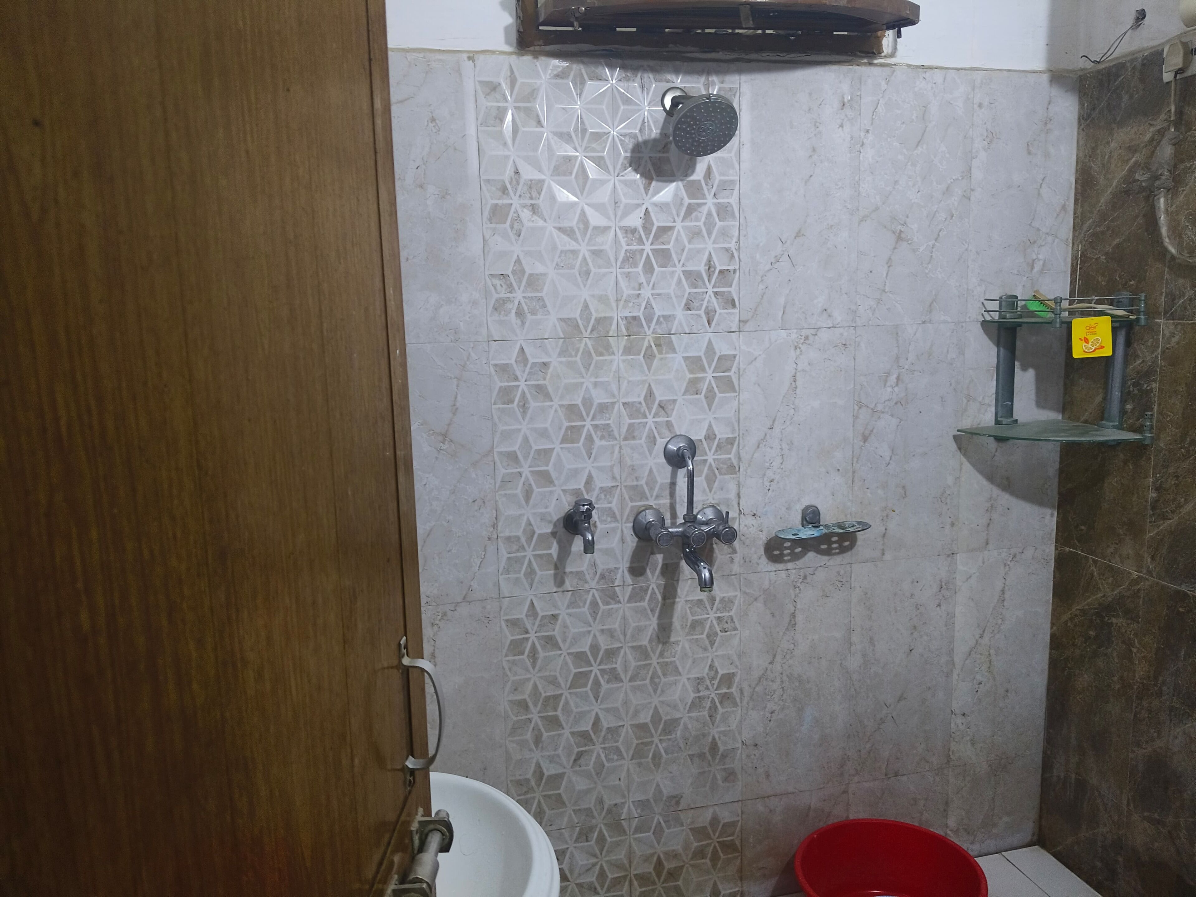 A bathroom with a shower, a sink, and a red basin.
