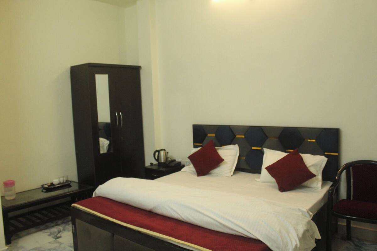 Habitación de hotel con cama, armario, una silla y una mesita con tetera.