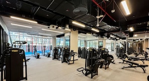 A gym with various exercise machines, large windows, and mirrors.