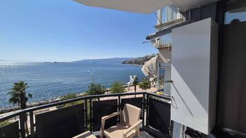 Un balcón con vista al mar, una silla y una mesa.