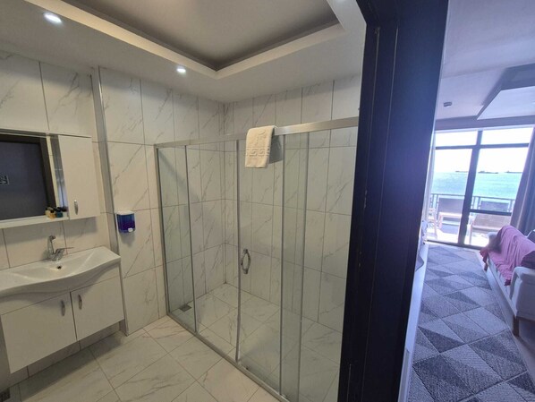 A modern bathroom with a glass-enclosed shower, a white sink, and a large mirror. - Barakat Suit Pansiyon (Gemlik)