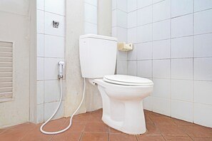 Un vàter blanc amb dipòsit i tapa, connectat a una palanca de tir fixada a la paret.