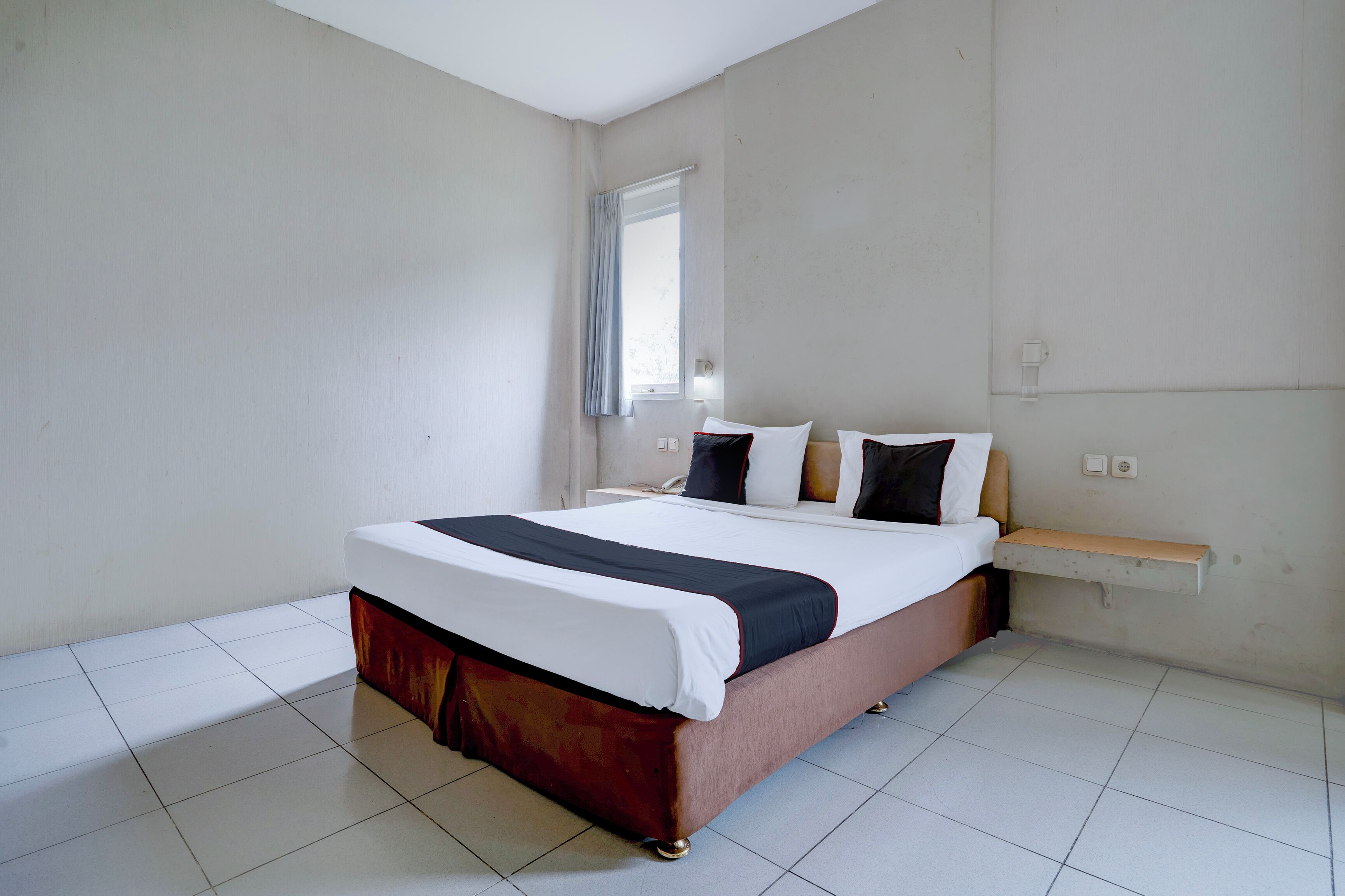 Ein Schlafzimmer mit Bett, Fenster und Nachttisch.