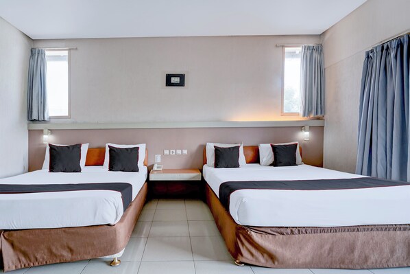 Habitación de hotel con dos camas, una mesita de noche, teléfono en la pared y una ventana con cortinas.