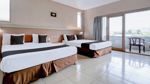 Habitación de hotel con dos camas, un ventanal grande y vistas a la ciudad.