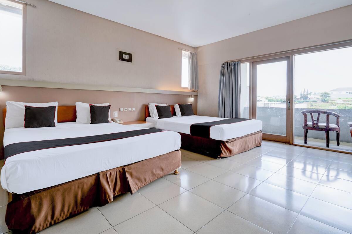 Habitación de hotel con dos camas, un ventanal grande y vistas a la ciudad.