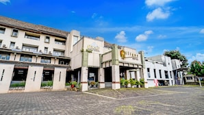 Un hotel con entrada central, varios pisos y un patio empedrado.