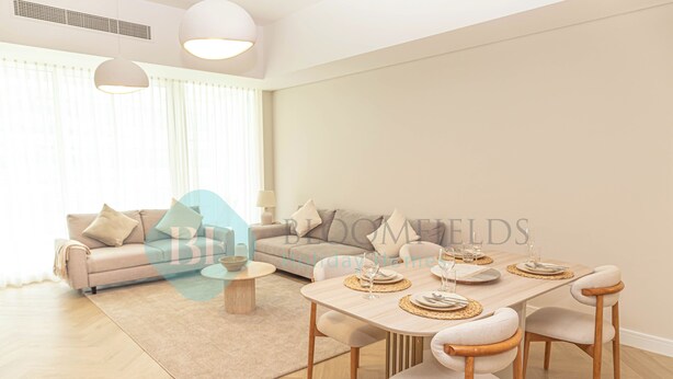 A modern living room with a sofa, dining table, and chairs. - Bloomfields Mayan 3BR Beach Access YAS (Abu Dhabi)
