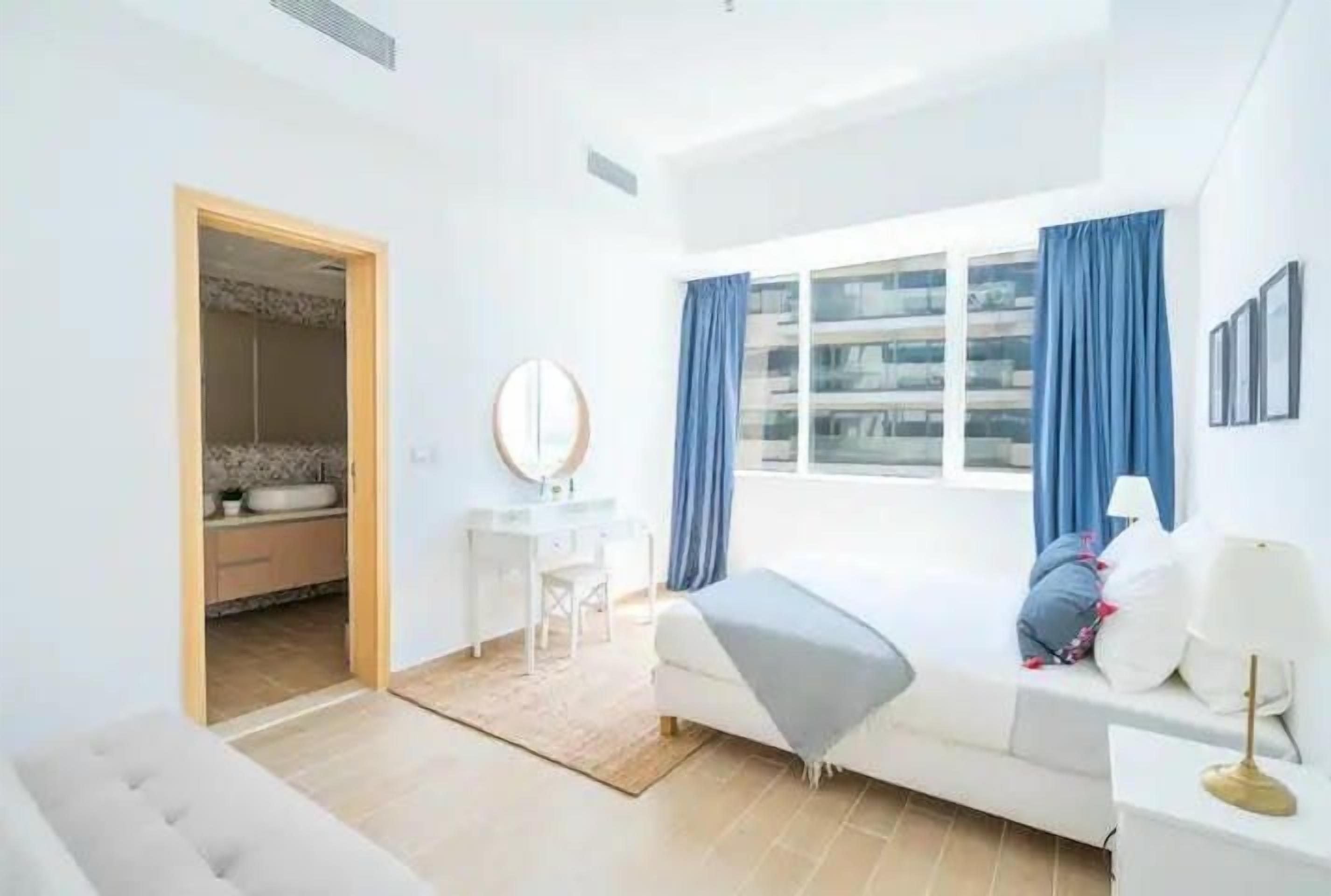 A modern bedroom with a bed, bedside table, and a window with curtains.