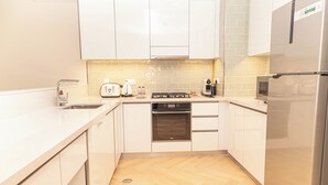 A modern kitchen with white cabinets, a stainless steel refrigerator, a built-in oven, and a microwave. - Bloomfields Mayan 3BR Beach Access YAS (Abu Dhabi)