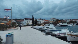 A marina with boats docked, a flagpole with a flag, and buildings in the background.