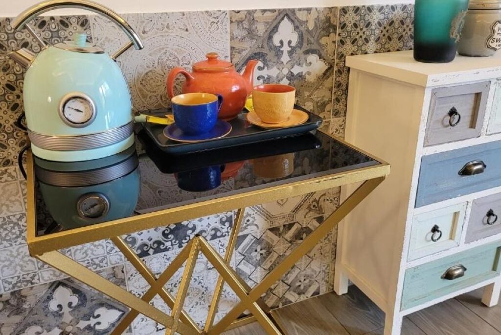 A kitchen with a vintage-style stove, a teapot, and a tray with cups.