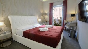 Habitación de hotel con una cama grande, una mesita de noche, una lámpara y vistas al exterior.