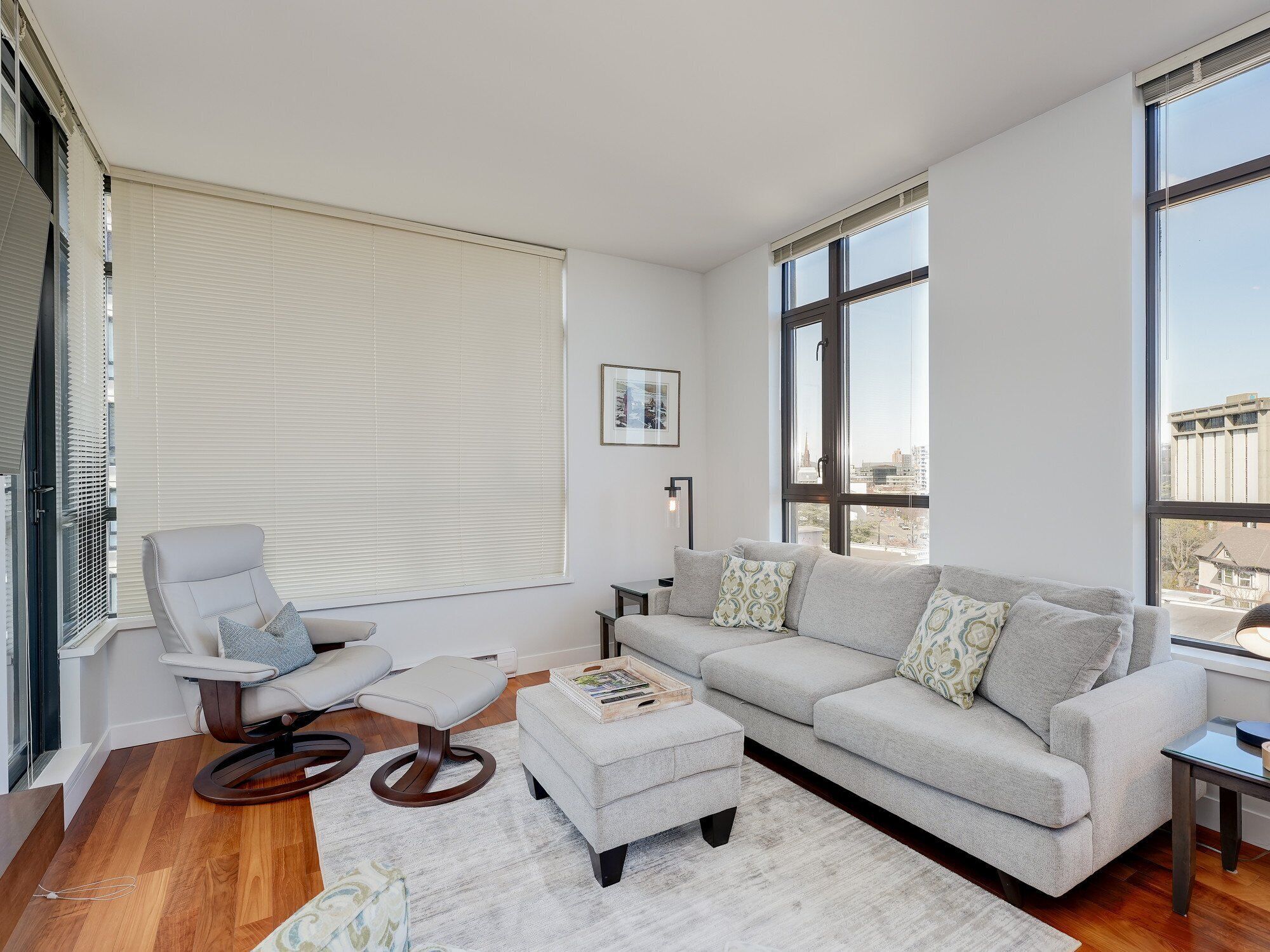 A modern living room with a grey sofa, a white armchair, and a wooden coffee table.