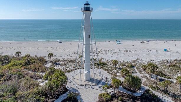 A lighthouse on a beach with clear skies and calm sea.