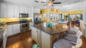 A modern kitchen with white cabinets, stainless steel appliances, and a central island with bar seating.