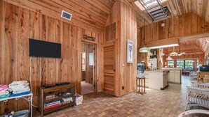 A wooden interior with a TV, a water dispenser, and a kitchen area.
