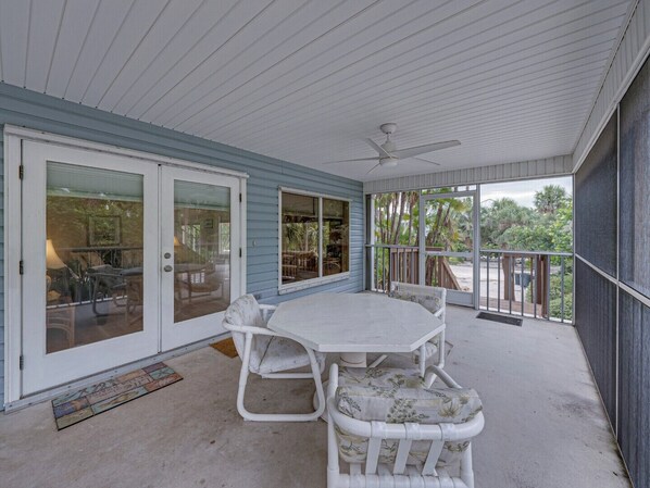 A covered patio with a table and chairs, a ceiling fan, and a view of the outdoors.