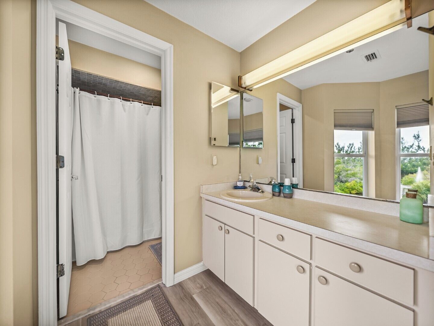 A bathroom with a shower, a sink, a mirror, and cabinets.