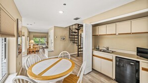 A modern kitchen with white cabinets, a black refrigerator, and a wooden dining table with chairs. - 2740 Shore Ln - 1 block to the peach - Pet Friendly!  Large Home (Boca Grande)