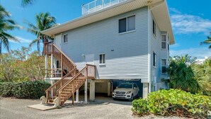 A two-story house with a covered garage and a car parked inside. - 2740 Shore Ln - 1 block to the peach - Pet Friendly!  Large Home (Boca Grande)