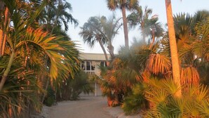 A pathway leading to a building surrounded by palm trees. - 2973 Shore Ln - 4 Bedroom - Beachfront Home (Boca Grande)