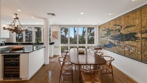 A spacious kitchen with a central island, large windows, and a dining area with wooden chairs. - 2973 Shore Ln - 4 Bedroom - Beachfront Home (Boca Grande)