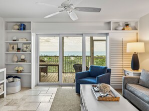 A living room with a view of the ocean, a ceiling fan, and a bookshelf with decorative items. - Sundown 03:  2-bed, 2-bath townhome in Boca Grande stunning Gulf front views, a relaxing getaway. (Boca Grande)