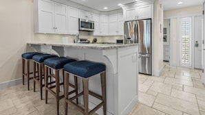 A modern kitchen with white cabinetry, stainless steel appliances, and a central island with bar stools. - Sundown 03:  2-bed, 2-bath townhome in Boca Grande stunning Gulf front views, a relaxing getaway. (Boca Grande)