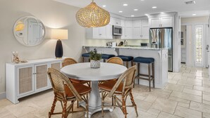 A modern kitchen with white cabinetry, a round dining table with wicker chairs, and a hanging light fixture. - Sundown 03:  2-bed, 2-bath townhome in Boca Grande stunning Gulf front views, a relaxing getaway. (Boca Grande)