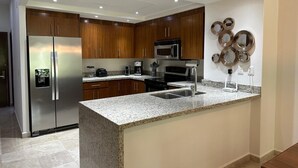 A modern kitchen with granite countertops, stainless steel appliances, and wooden cabinets.