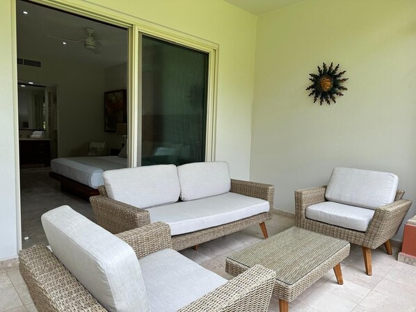 Un espacio habitable con mobiliario de mimbre, un sofá, un sillón y una mesita.