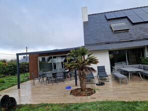 A modern house with a patio, a glass enclosure, and a palm tree. - Weekly rental house with a swimming pool, 5 km from the beach (Plonéour-Lanvern)