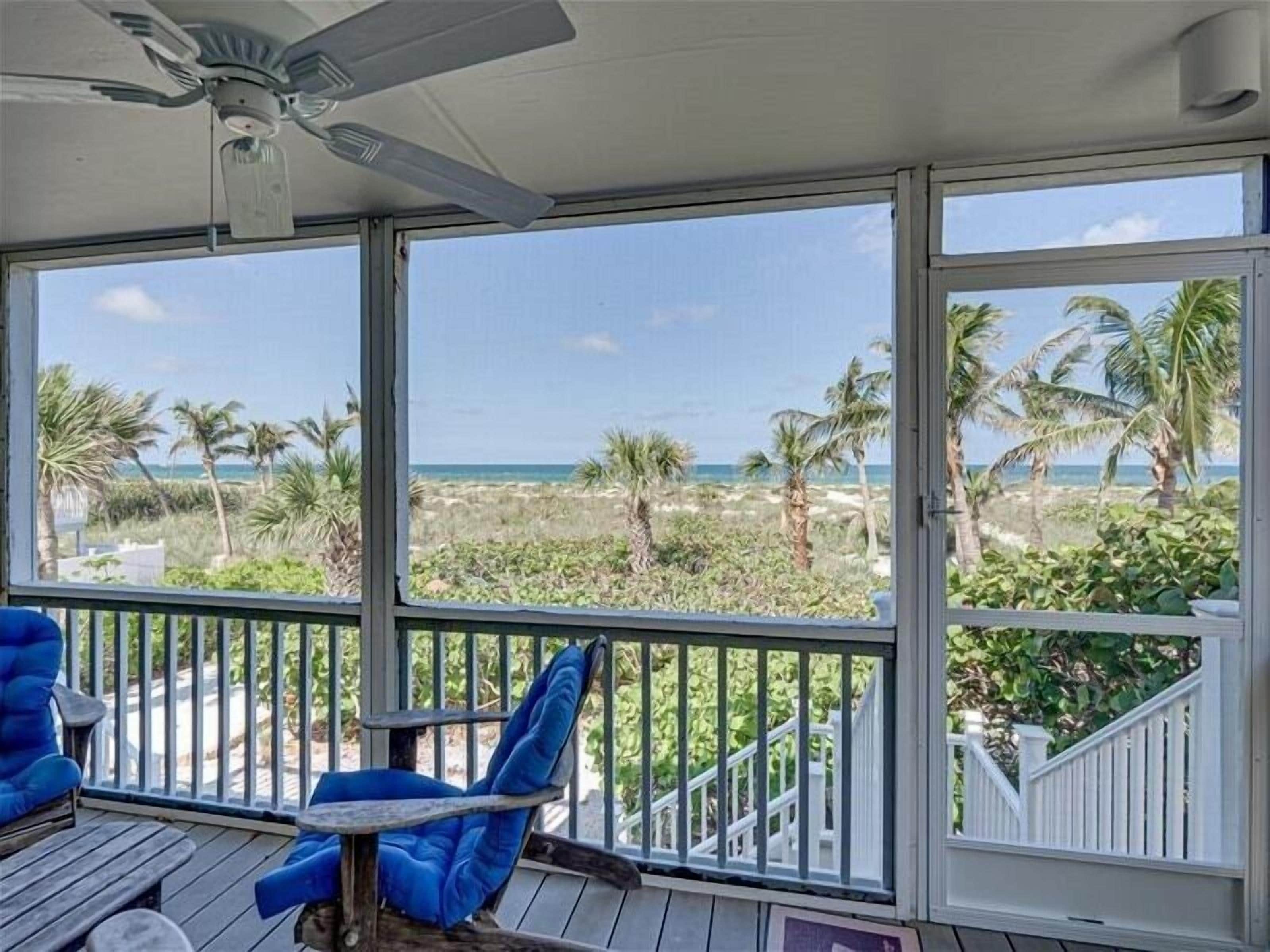 Ein Balkon mit Blick auf den Strand, ein Deckenventilator und ein blauer Sitzkorb.