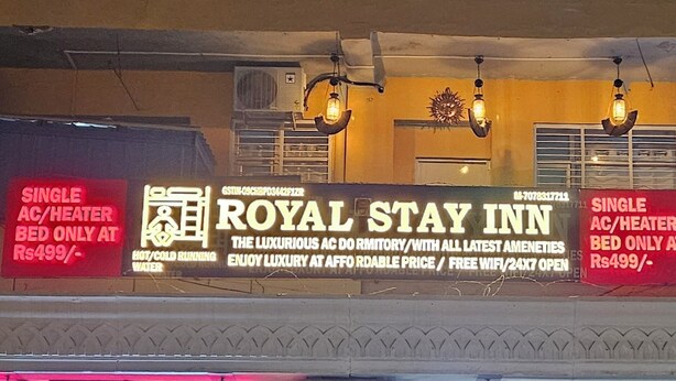 A Royal Stay Inn signboard advertising single AC/heater beds at Rs499/- with amenities like hot/cold running water, luxury, affordable price, free WiFi, and 24x7 open. - Royal Stay Inn (Moradabad)