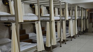 A dormitory with bunk beds, each with a curtain and a fan. - Royal Stay Inn (Moradabad)