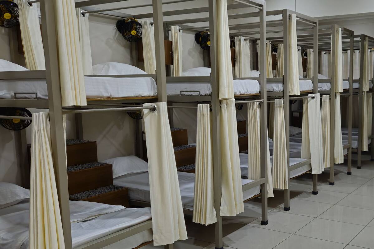 A dormitory with bunk beds, each with a curtain and a fan.