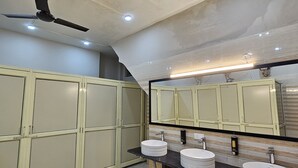 A bathroom with a mirror, two sinks, and a ceiling fan. - Royal Stay Inn (Moradabad)