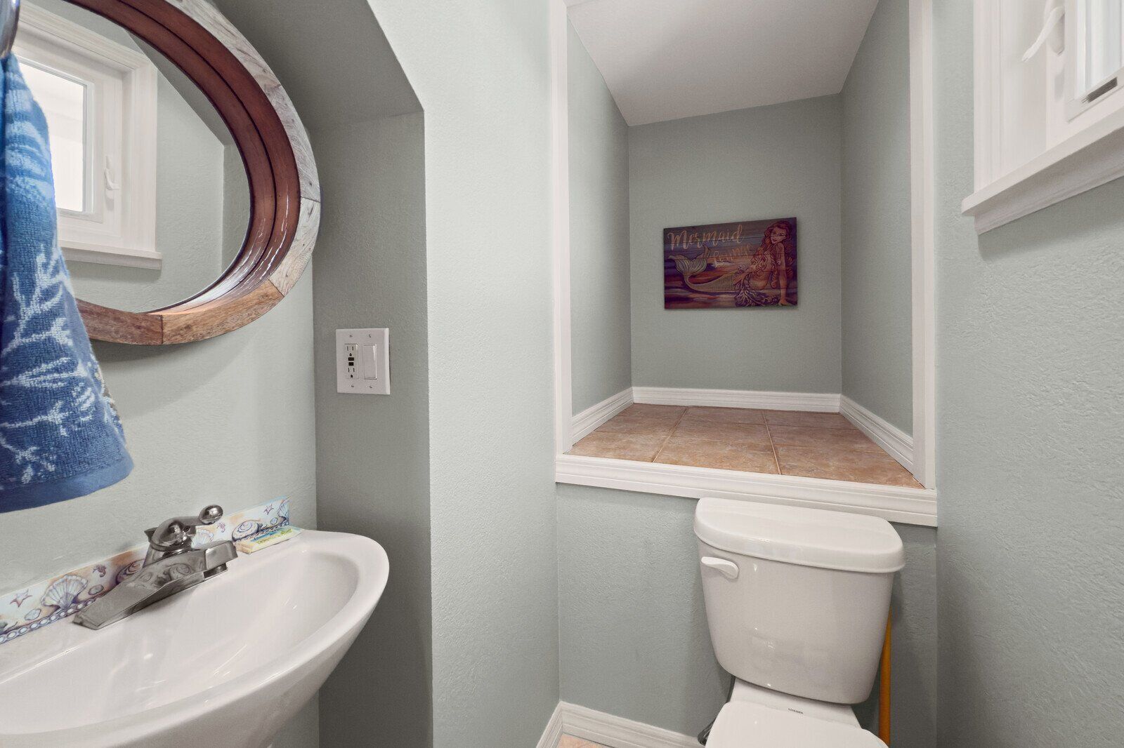 A bathroom with a sink, toilet, and a small window sill.