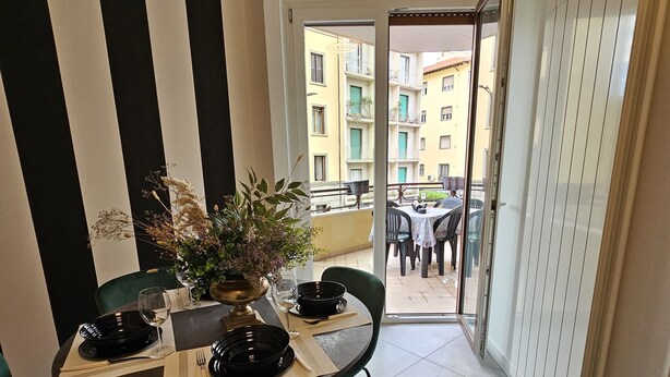 A dining area with a round table set for four, green chairs, and a potted plant. - Vivaldi Suite (Firenze)