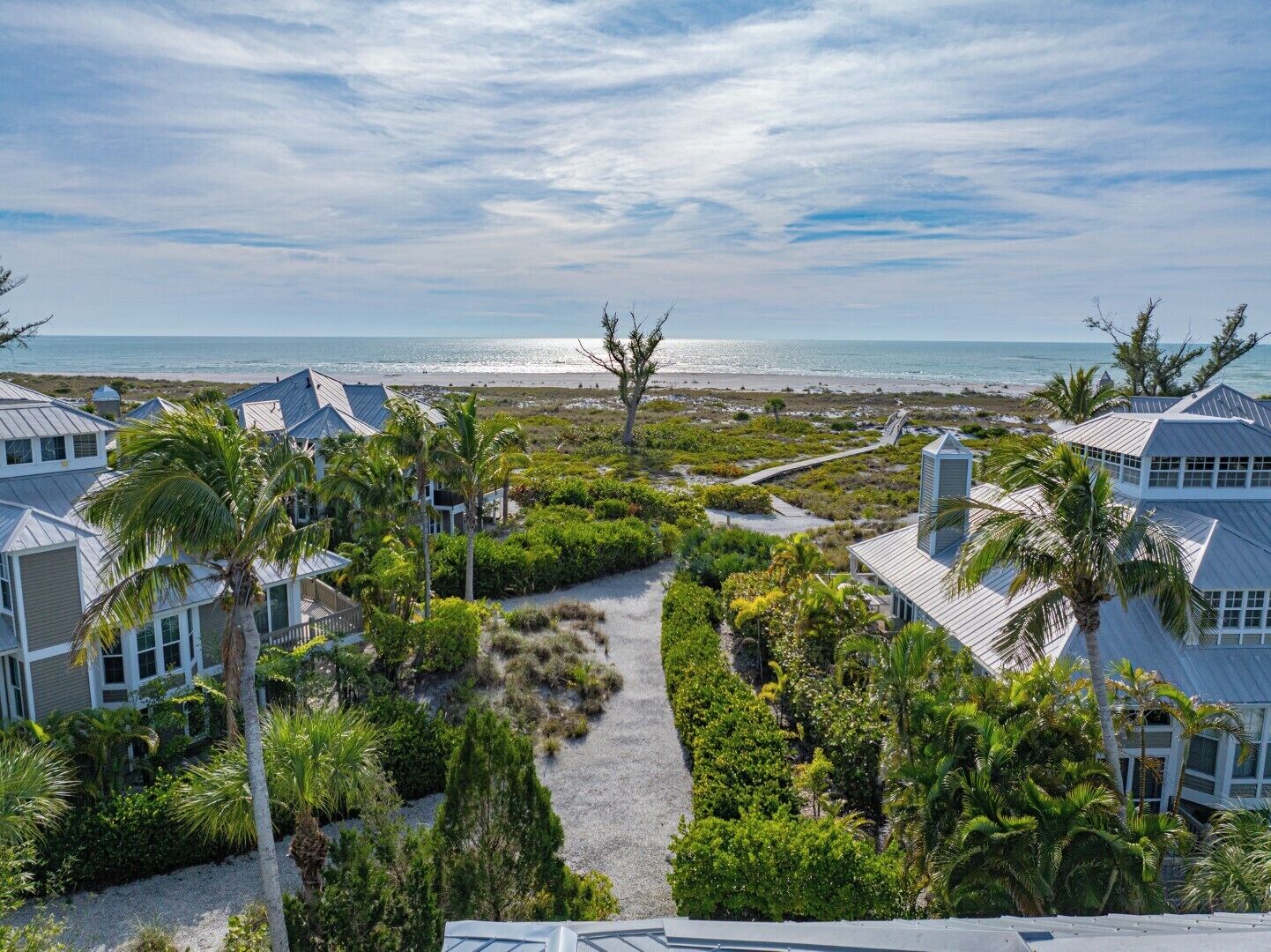 A coastal property with multiple buildings, a pathway, and a view of the beach and ocean.
