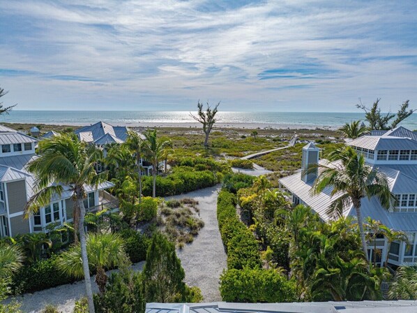 A coastal property with multiple buildings, a pathway, and a view of the beach and ocean.