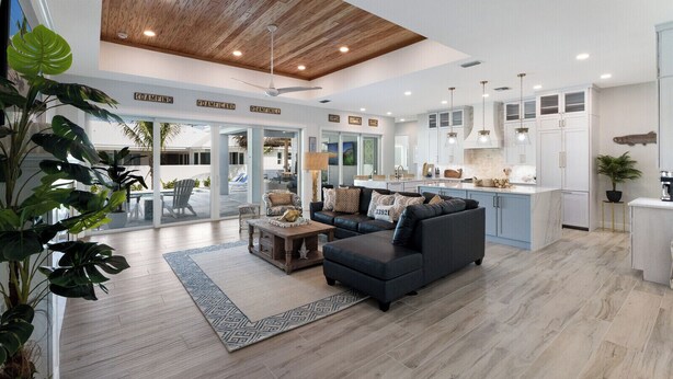 A spacious living area with a modern kitchen, a ceiling fan, and a large window overlooking a pool.