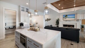 A modern kitchen with a marble island, built-in appliances, and pendant lighting.