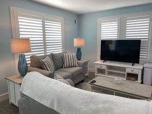 A living room with a sofa, two lamps, a TV, and a coffee table. - Fun Spot in Downtown Boca GRande - 1/1  apartment above the Temp Restaurant ! (Boca Grande)