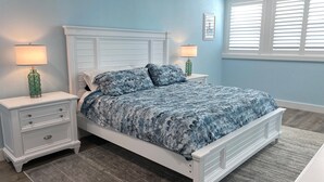 A bedroom with a bed, two nightstands, and a window with blinds.