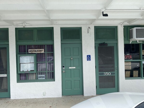 Un edificio con tres puertas verdes, una con la etiqueta 'RESTAURANT' y otra con un letrero de 'CERRADO'. Se observa un símbolo de accesibilidad para sillas de ruedas, y el número '35' en la puerta derecha.