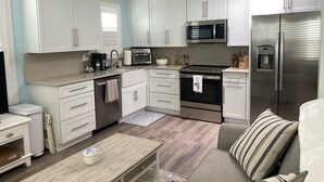 A modern kitchen with white cabinets, stainless steel appliances, and a wooden dining table.
